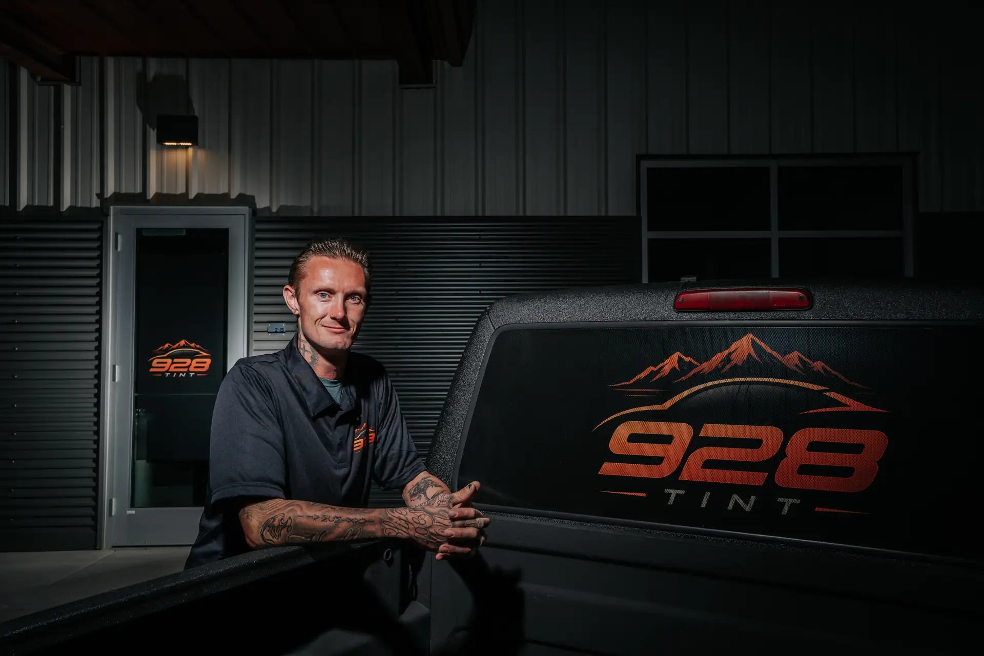 Jonny Martin, owner of 928 Tint, leaning on a truck tailgate with the 928 Tint logo